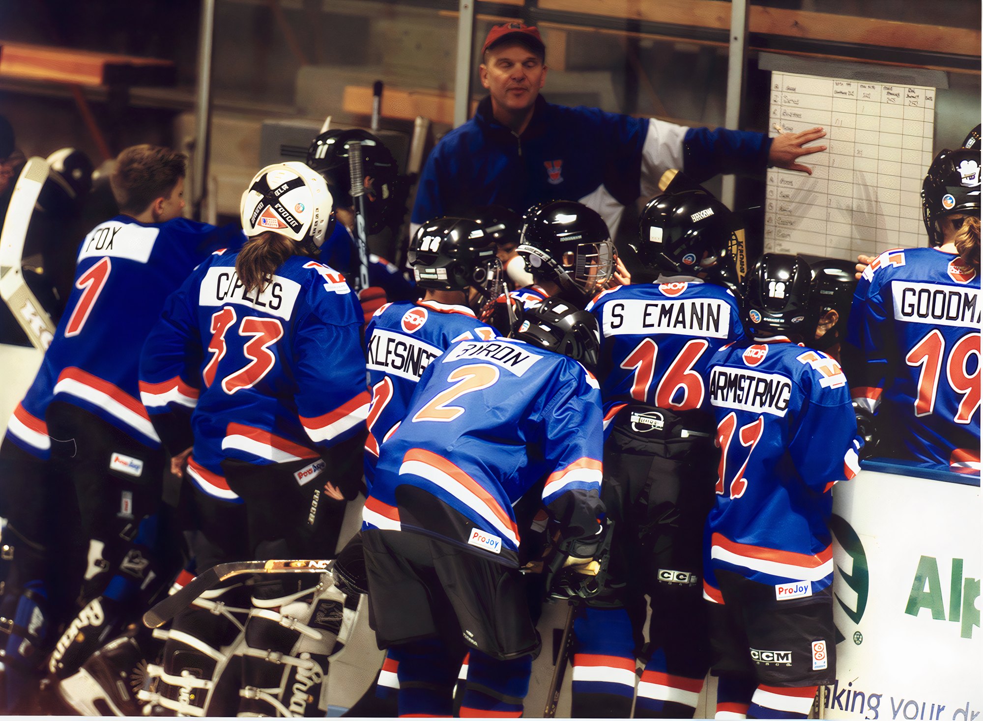 Barry Biegler coaching his Vail team in a huddle at the boards, pointing to the lineup board